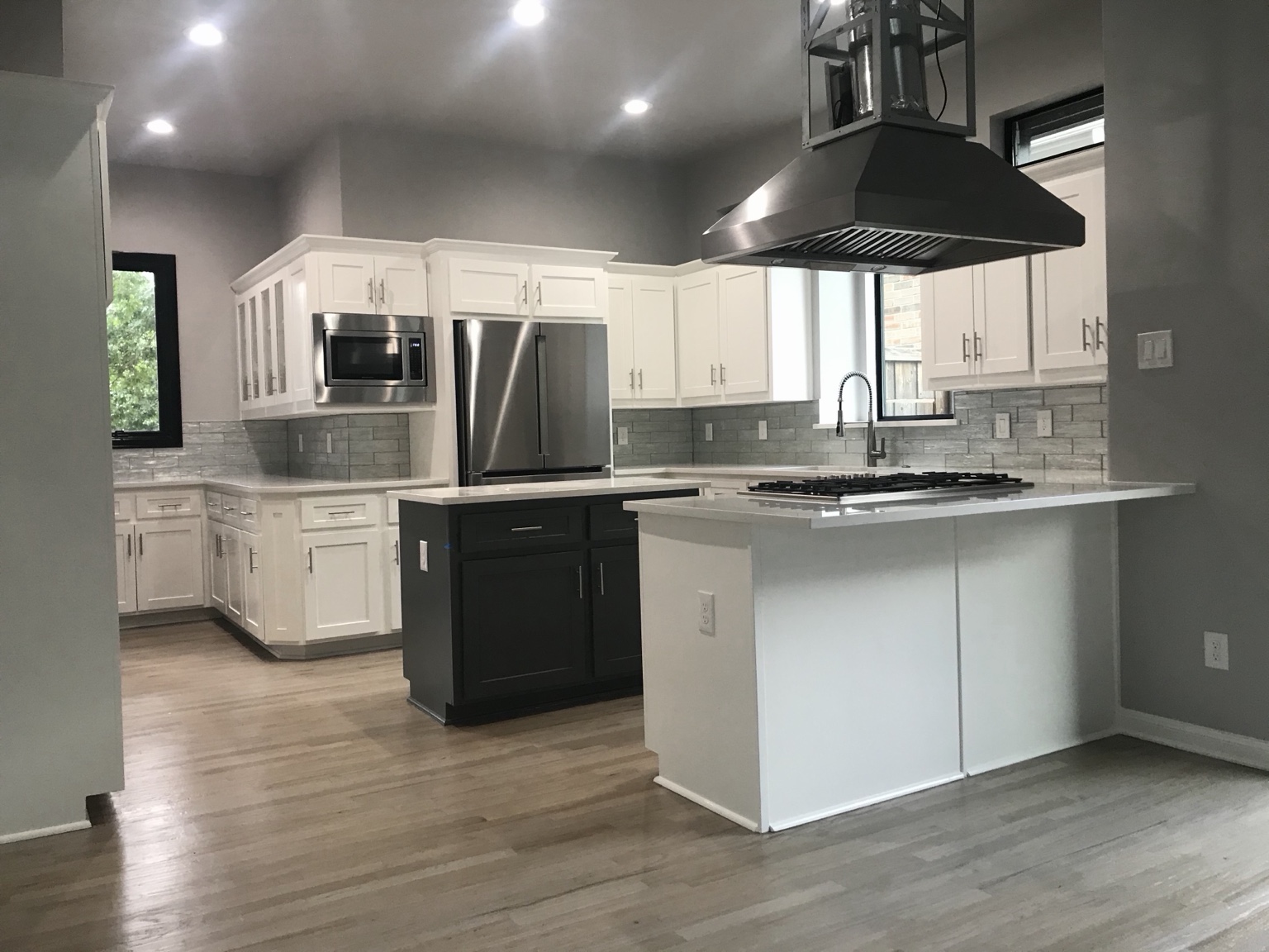 Modern white kitchen with black island and vent hood