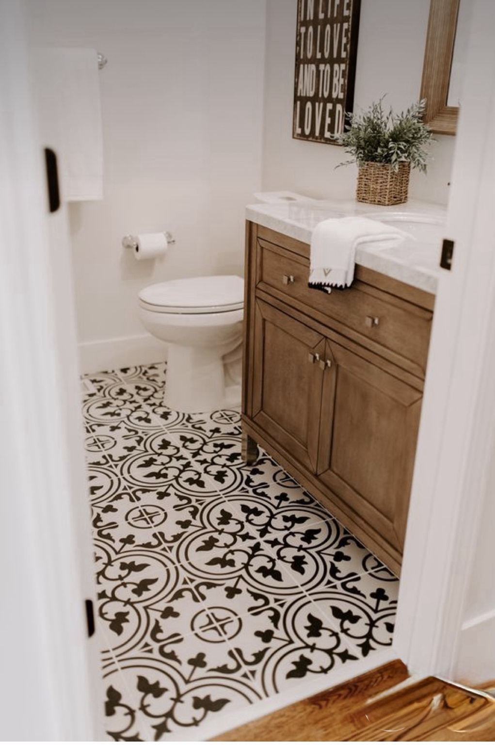 Bathroom with patterned black and white floor tile and wood vanity